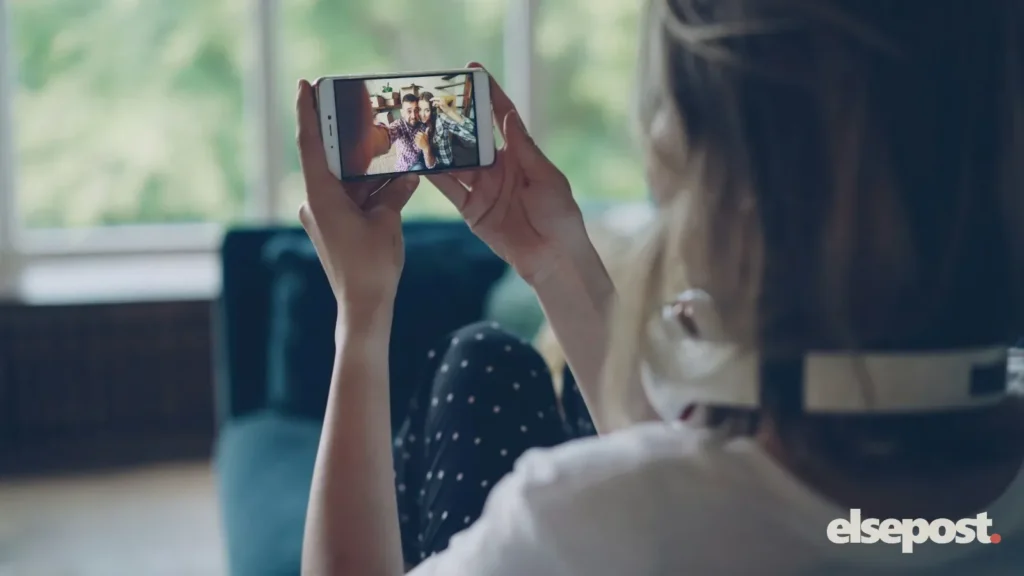 A woman holding a smartphone sideways to watch a video at home