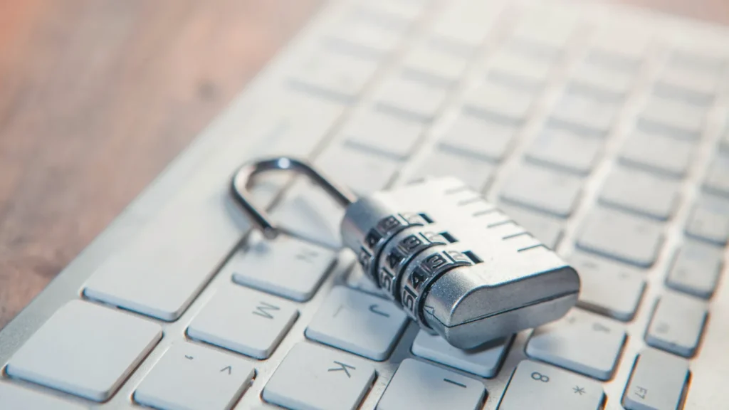 An open combination padlock resting on a white computer keyboard
