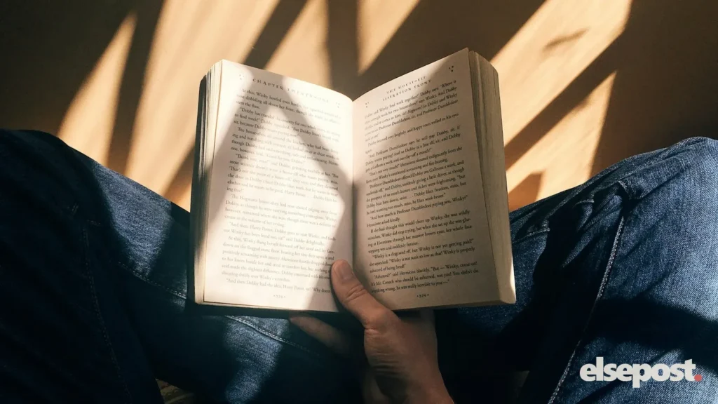 A person reading an open book in warm light