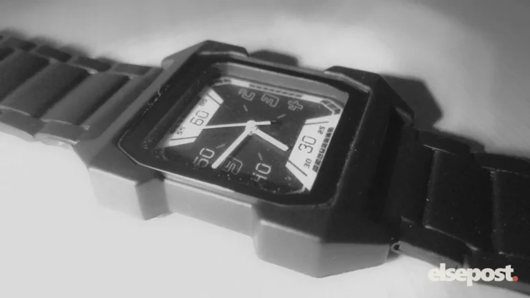Close-up of a square black analog resin watch on a white surface