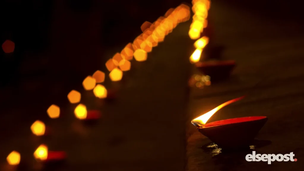 A row of lit clay diyas glowing in warm light