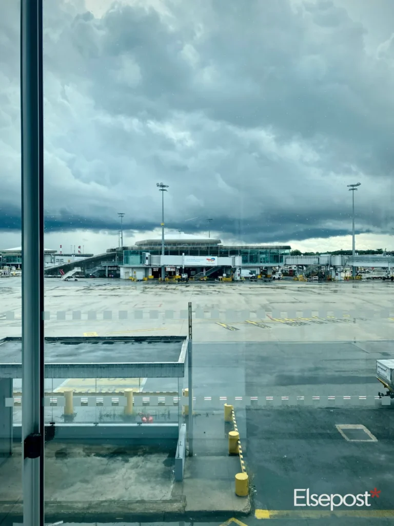 Flight delay fog rules India: an airport seen through a terminal window on a cloudy day