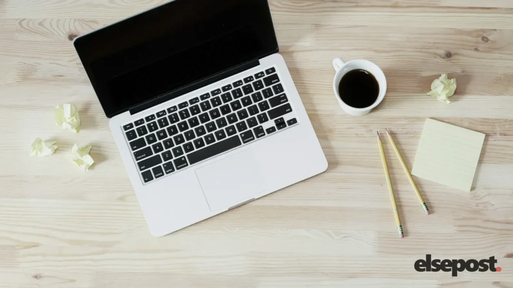 A laptop, sticky notes, pencils and a cup of coffee on a wooden desk