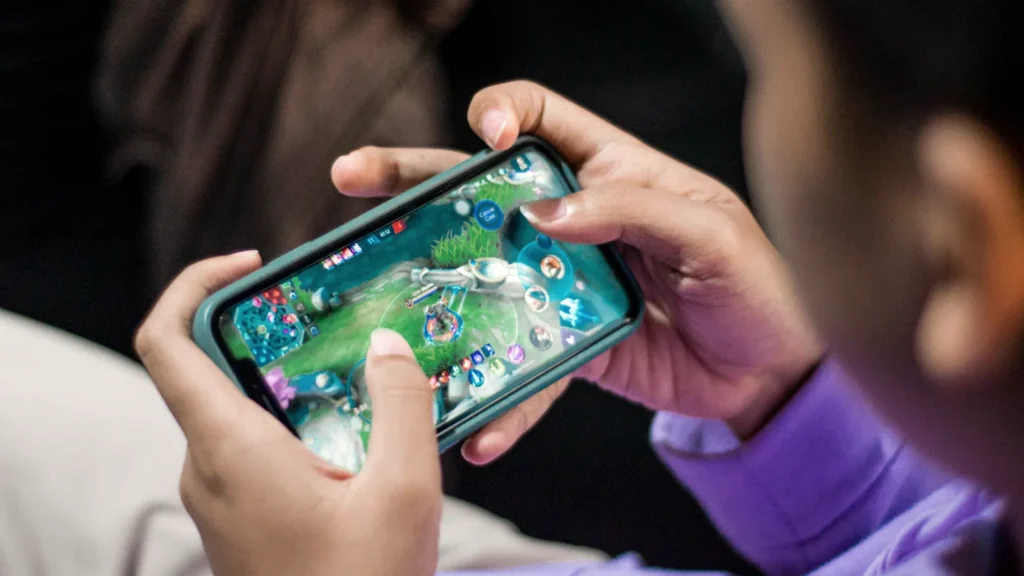 Close-up of two hands holding a smartphone sideways while playing a mobile game
