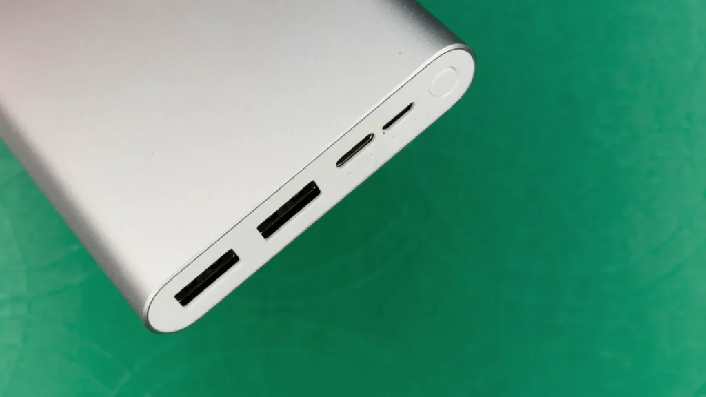 A silver power bank showing its USB ports, on a green background