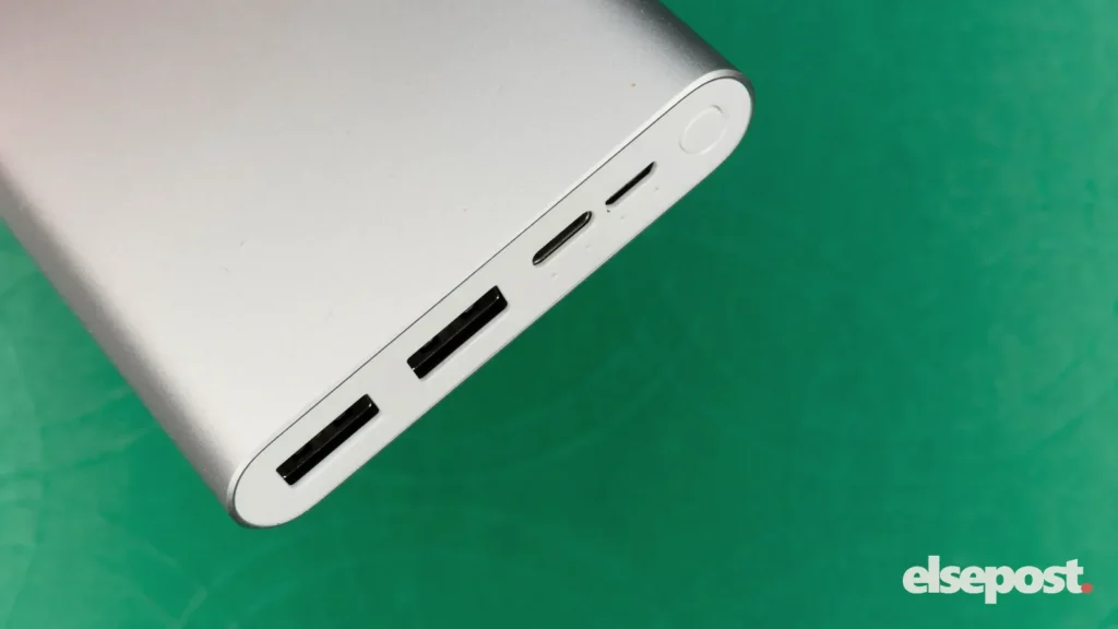 A silver power bank showing its USB ports, on a green background