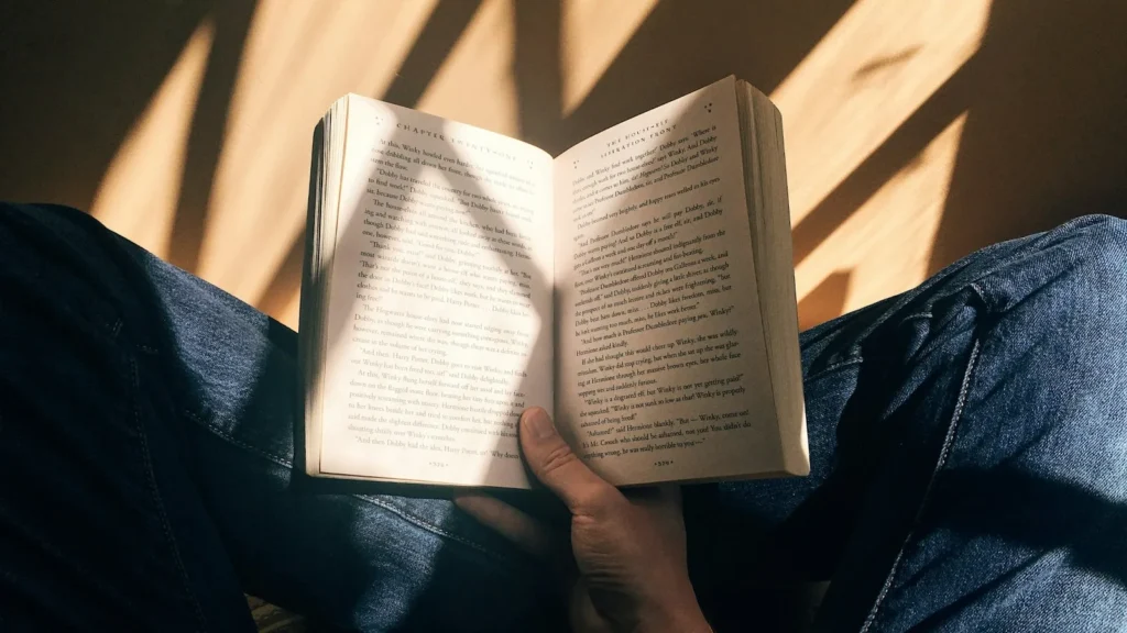 A person reading an open book in warm light
