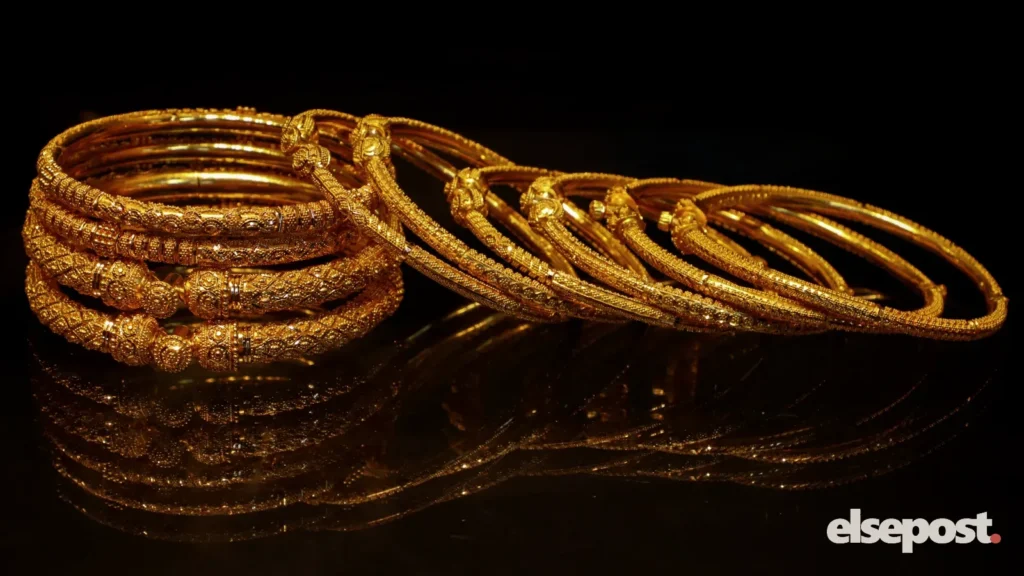 Stacked gold bangles with fine engraved patterns on a dark surface