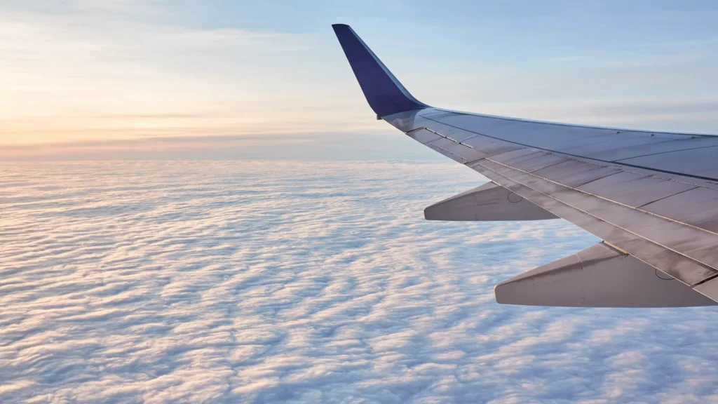 Airplane wing above white clouds during the day