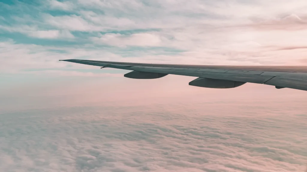 An aircraft wing above a layer of clouds at dusk
