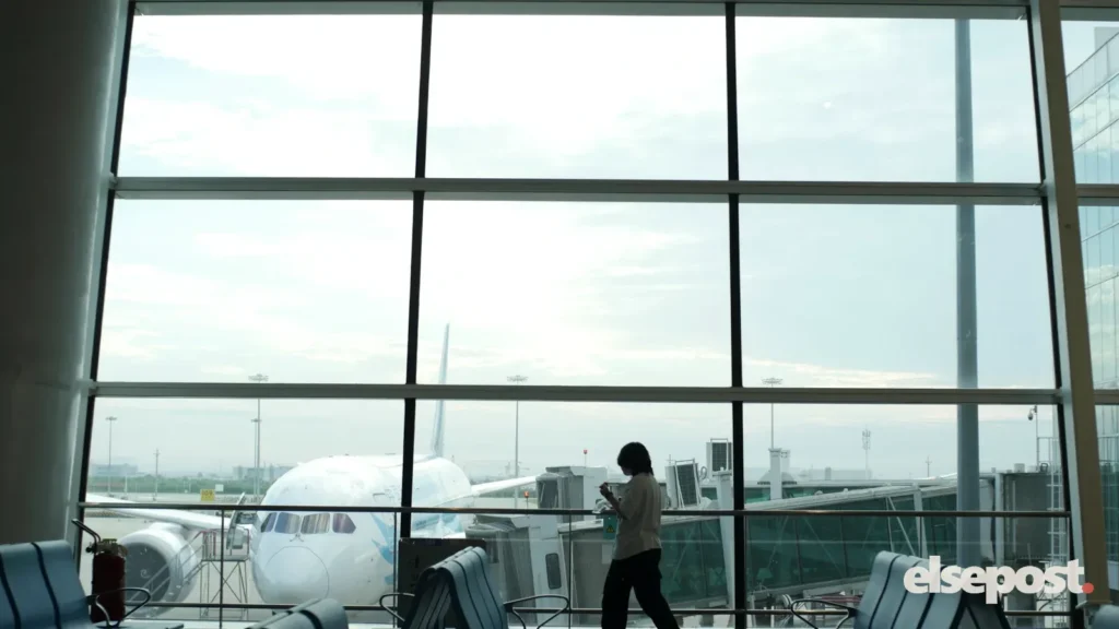 Traveller looking out of an airport window at a plane, smart travel in India