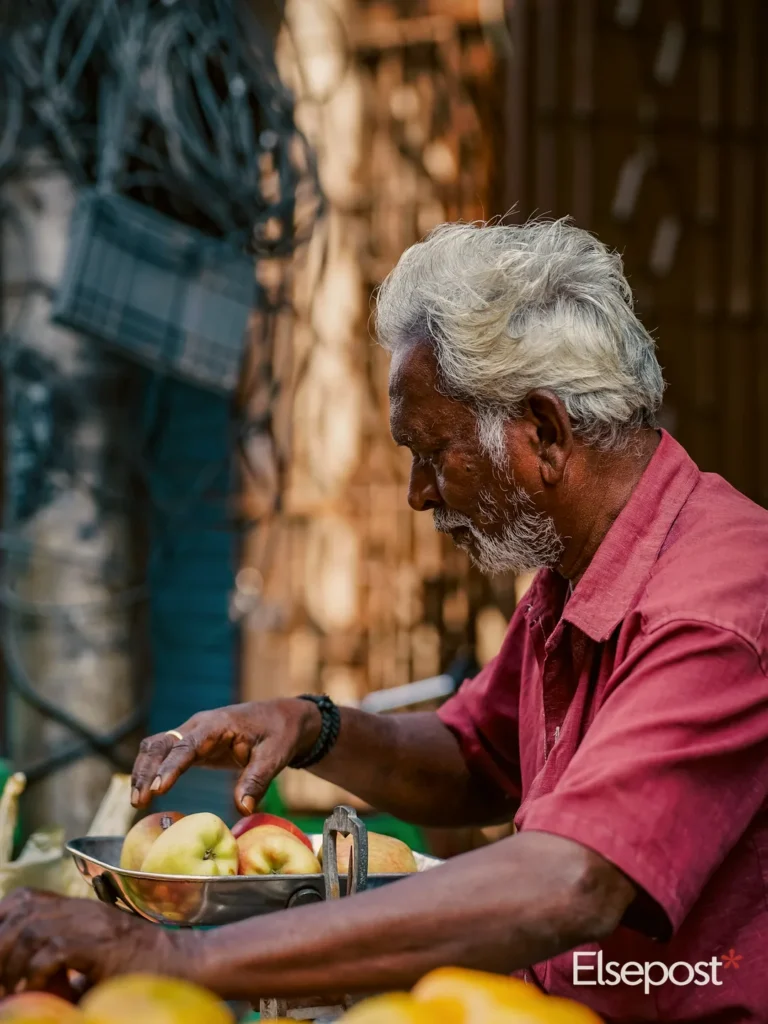 An elderly vendor weighs apples at a street market stall, a place where small UPI Lite payments are common