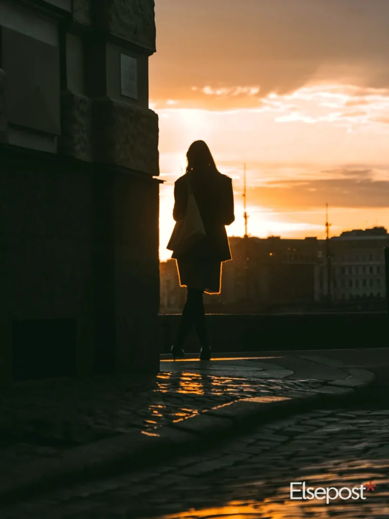 Woman walking down a street at sunset