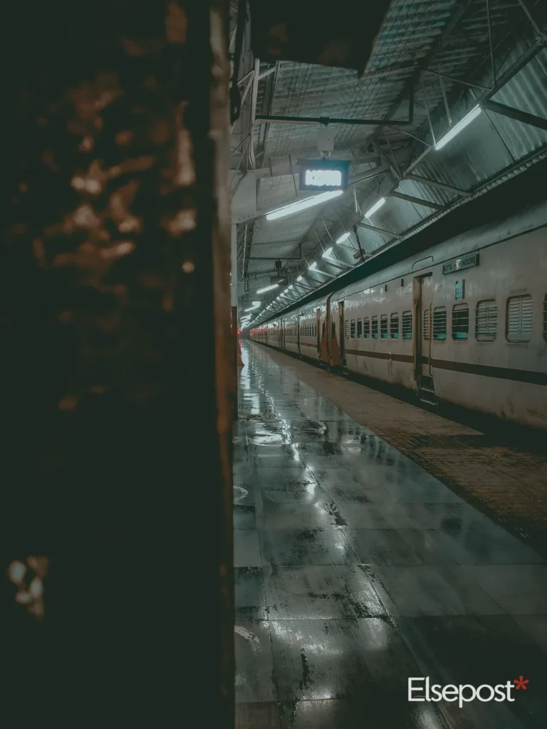 Long overnight train standing at a wet railway platform at night