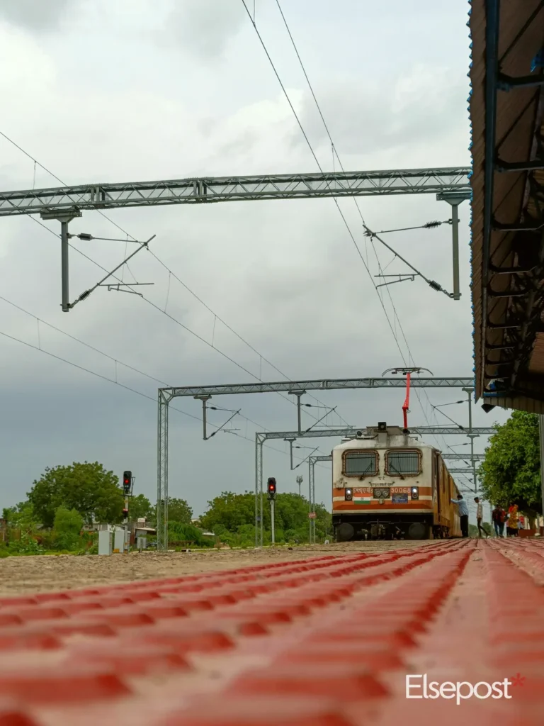 Express train approaching a railway platform under cloudy skies