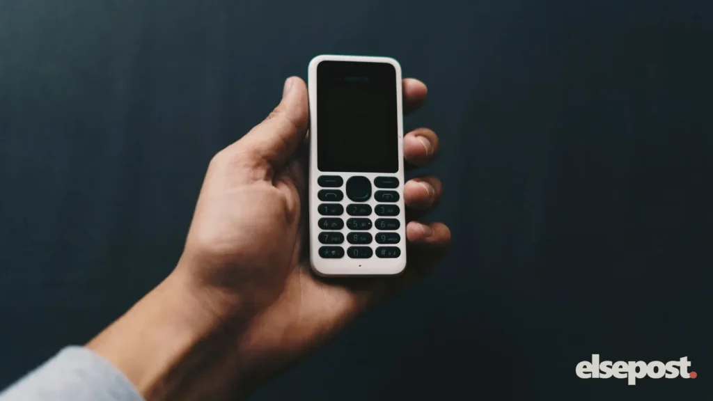 A hand holding a basic keypad mobile phone